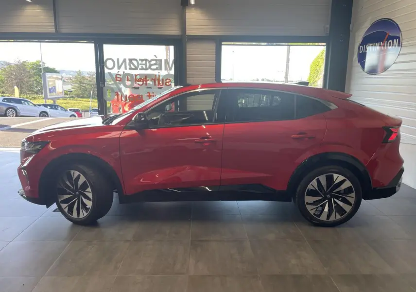 Vue de profil côté gauche d'une Renault Rafale rouge avec toit noir et jantes alliage noires en intérieur showroom.