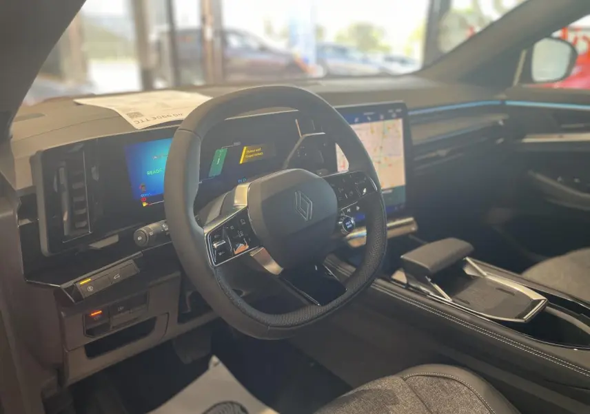 Vue intérieure côté conducteur du Renault Rafale 2025, volant noir avec logo Renault et écran tactile central lumineux.