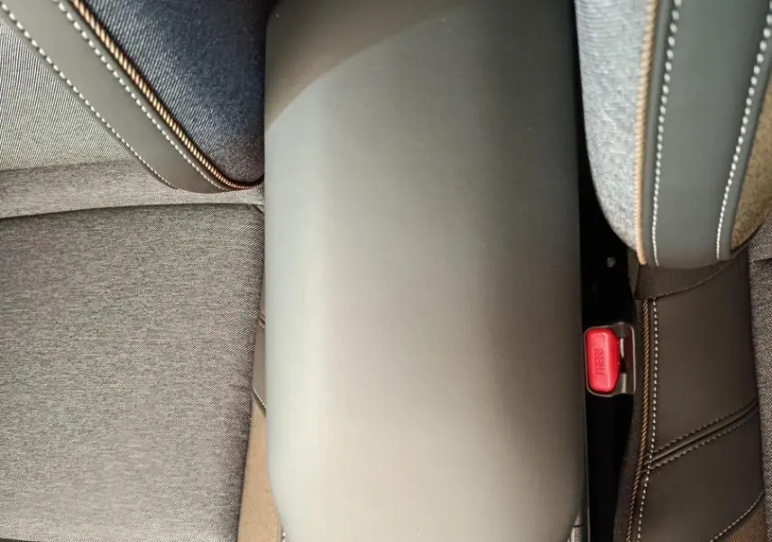 Vue plongeante sur l'accoudoir central gris et les sièges tissu gris du Renault R5 Techno 150 ch 2025.