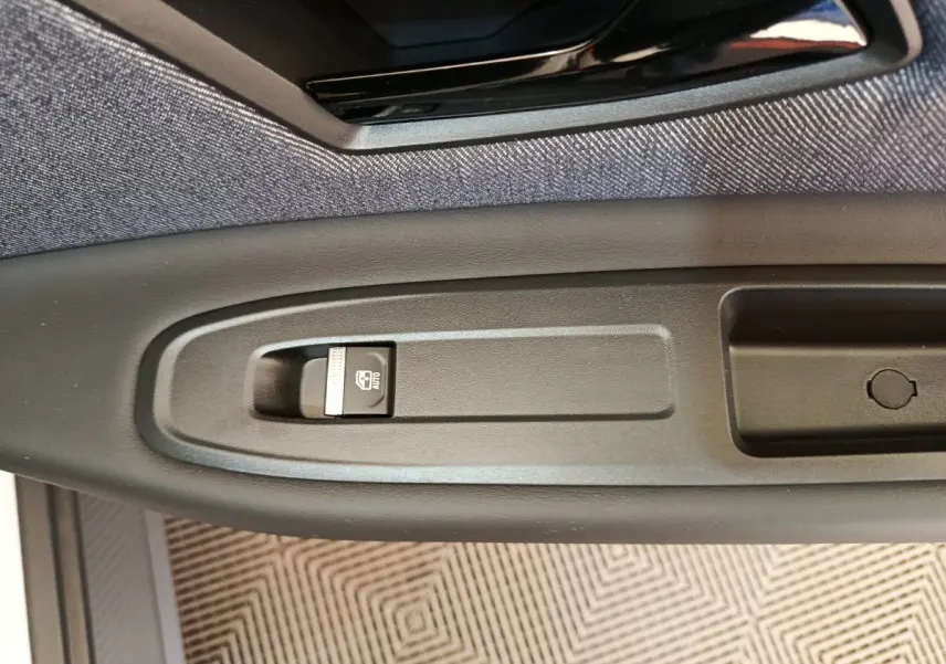 Gros plan sur le bouton de commande de la fenêtre électrique côté conducteur de la Renault R5 Techno 150 ch blanche 2025.