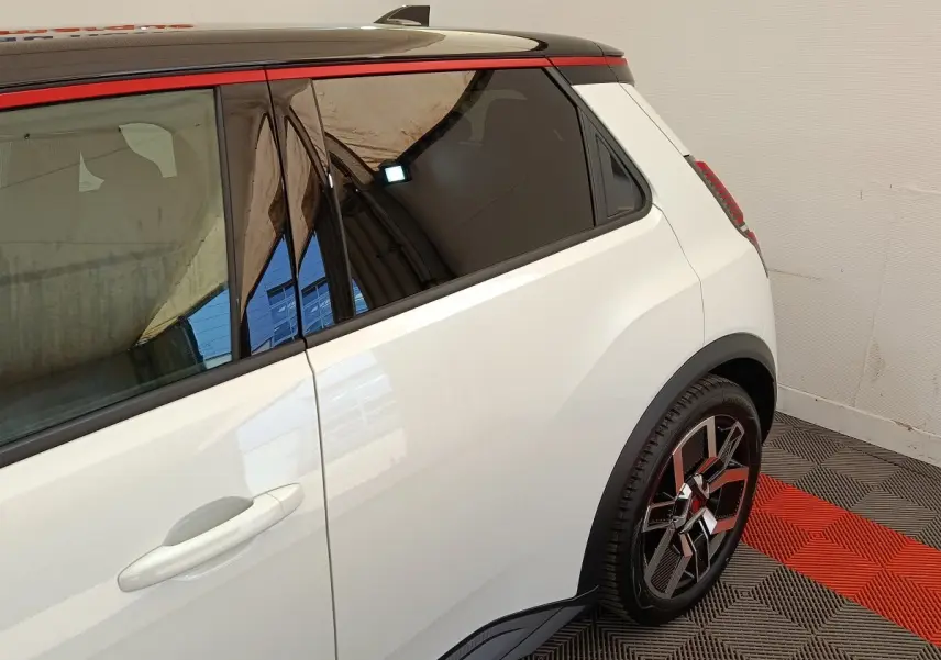 Vue latérale droite arrière d'une Renault R5 Techno blanche avec toit noir et jantes stylisées multicolores.