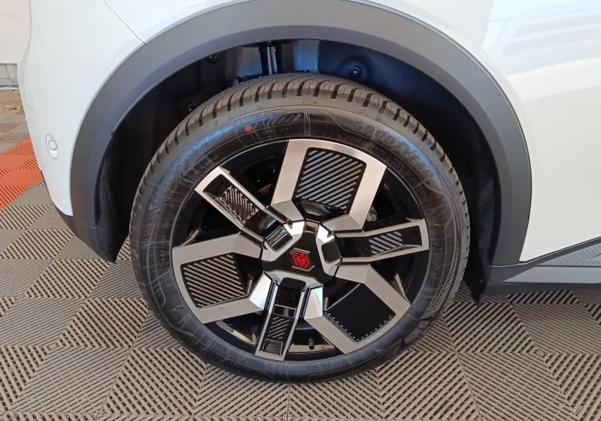 Gros plan sur la roue avant droite blanche d'une Renault R5 Techno 150 ch avec jante noire et argentée au design géométrique.