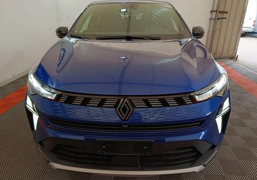 Vue frontale d’une Renault Symbioz bleu électrique avec calandre noire et phares LED allumés dans un garage.