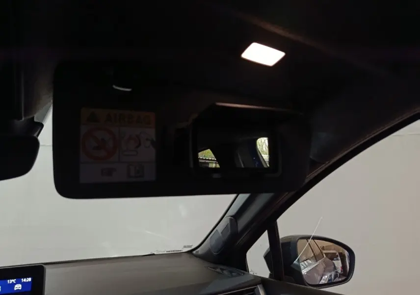 Intérieur côté conducteur du Renault Symbioz bleu, avec pare-soleil rabattu et miroir éclairé visible.