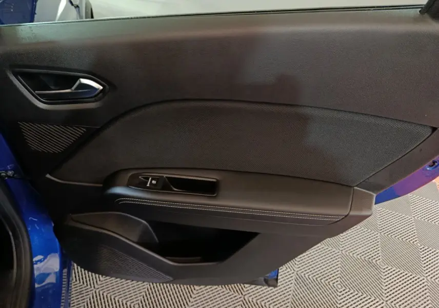 Vue intérieure côté gauche de la porte avant bleu Renault Symbioz 2025 avec poignée et commande de vitre noire.