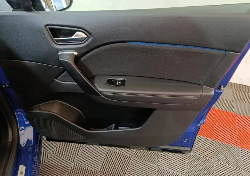 Vue intérieure de la porte avant gauche bleu Renault Symbioz 2025, avec poignée argentée et commande de fenêtre.