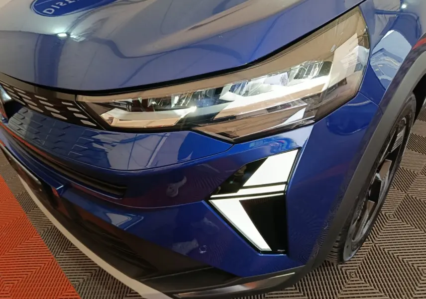 Gros plan sur l'avant droit bleu du Renault SYMBIOZ 2025, mettant en valeur ses phares LED et feux diurnes en forme de flèche.