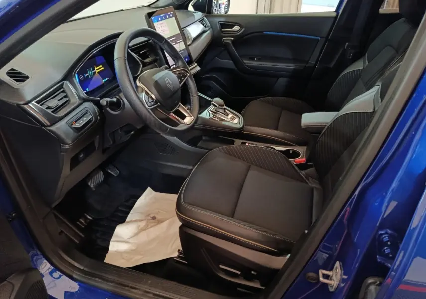 Vue intérieure côté conducteur de la Renault SYMBIOZ bleu, avec tableau de bord digital et écran tactile central.