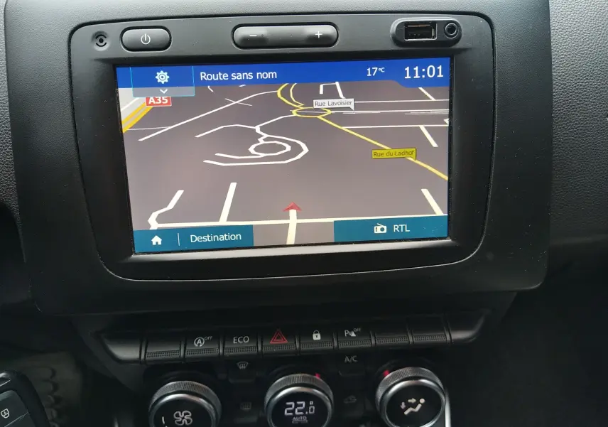 Vue rapprochée de l'écran GPS et de la console centrale noire du Dacia Duster gris 2020 avec commandes de climatisation.