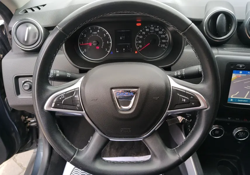 Vue rapprochée du volant noir du Dacia Duster 2020 avec tableau de bord et écran GPS visible à droite.