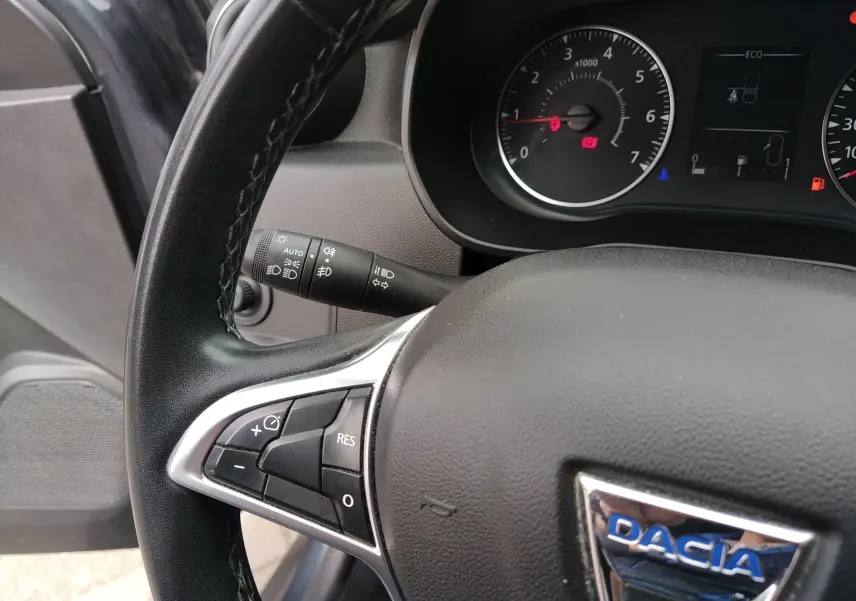 Gros plan sur le volant noir du Dacia Duster 2020, avec commandes intégrées et tableau de bord partiellement visible.