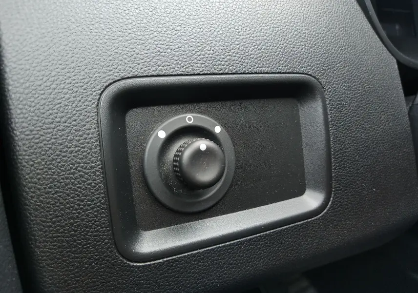 Bouton de réglage noir sur tableau de bord texturé gris foncé du Dacia Duster 2020, vue rapprochée intérieure.