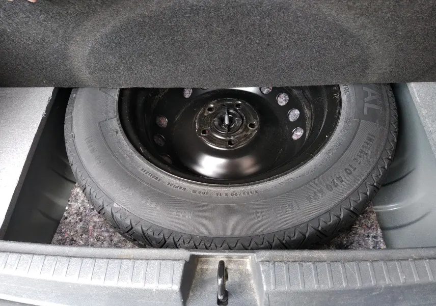 Vue rapprochée de la roue de secours noire dans le coffre d'un Dacia Duster gris 2020, version Prestige.
