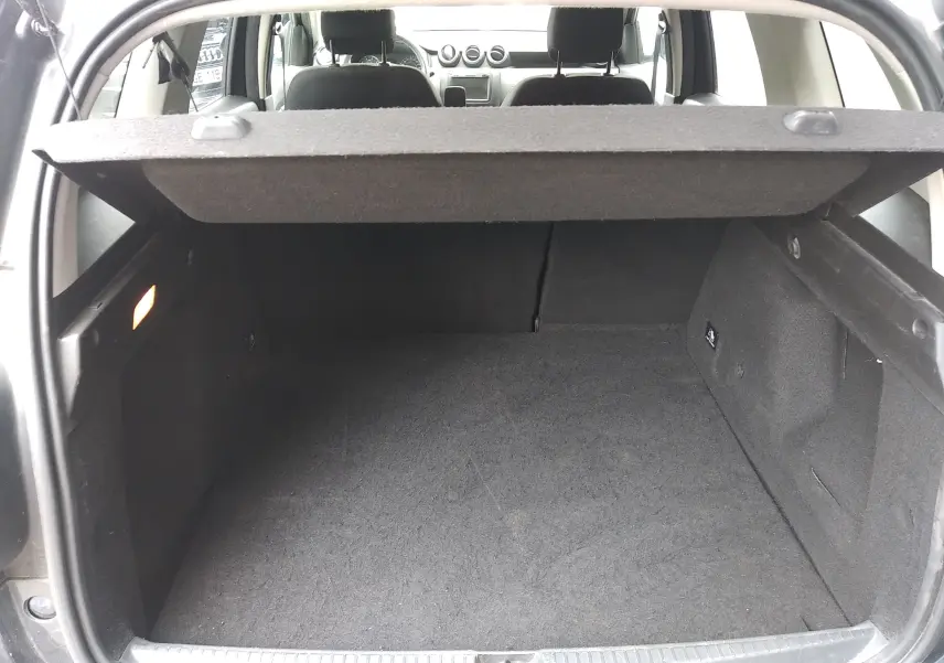 Coffre ouvert d'un Dacia Duster gris 2020, vue intérieure arrière montrant l'espace de chargement et la tablette cache-bagages.