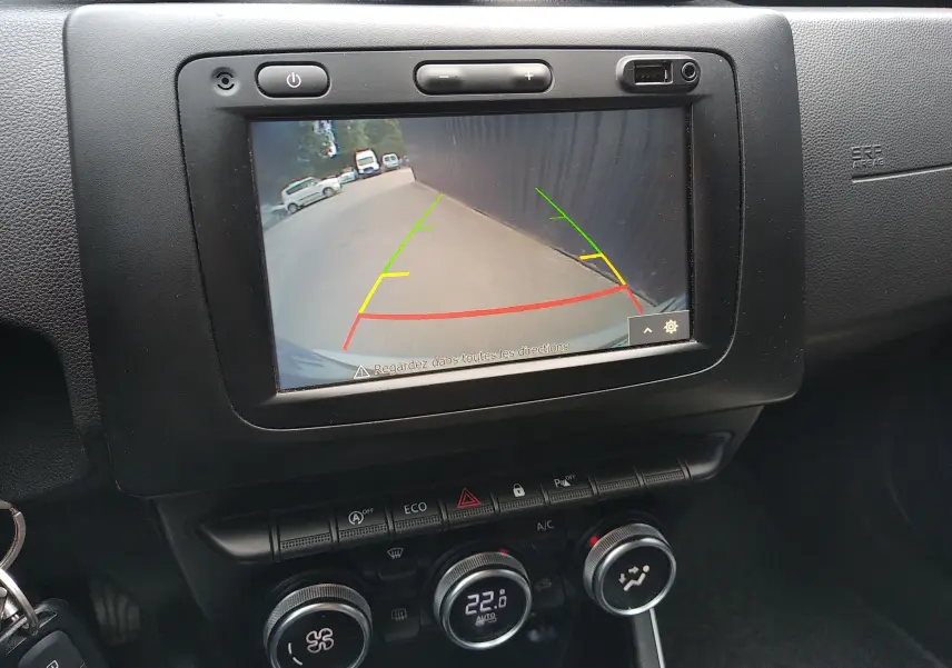 Écran central du Dacia Duster 2020 montrant la caméra de recul avec guidage coloré, tableau de bord noir.