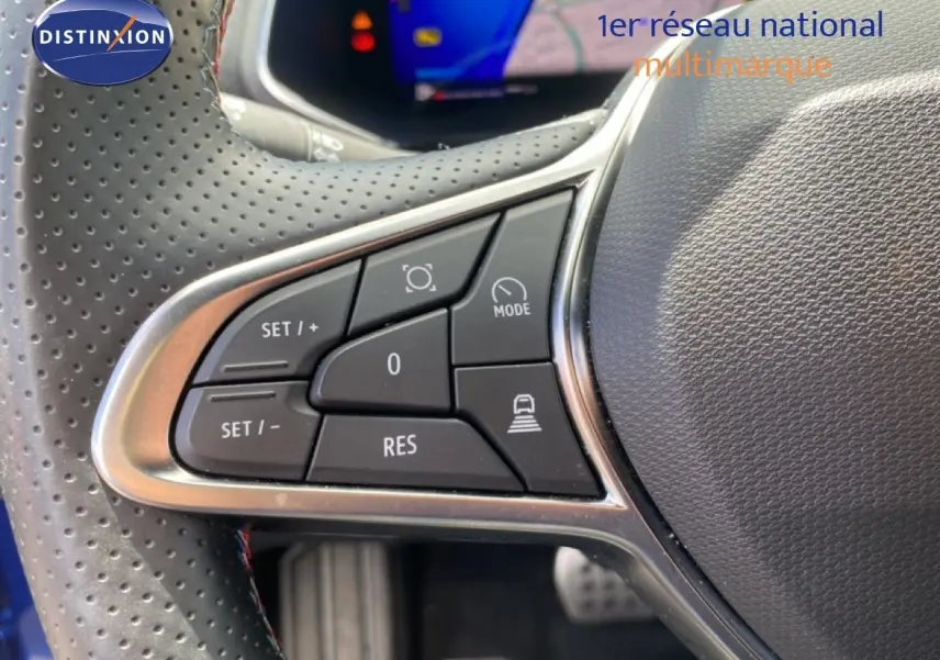Gros plan sur les commandes au volant côté gauche d’une Renault Symbioz bleu Iron Metal, affichage numérique en arrière-plan.