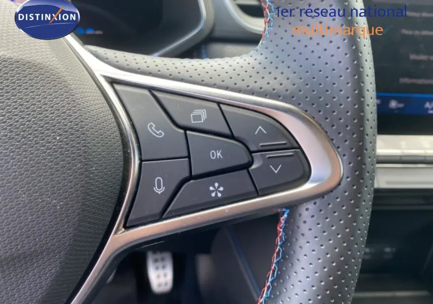 Gros plan sur les commandes au volant côté gauche du Renault Symbioz E-Tech Full Hybrid 2025 avec surpiqûres tricolores.