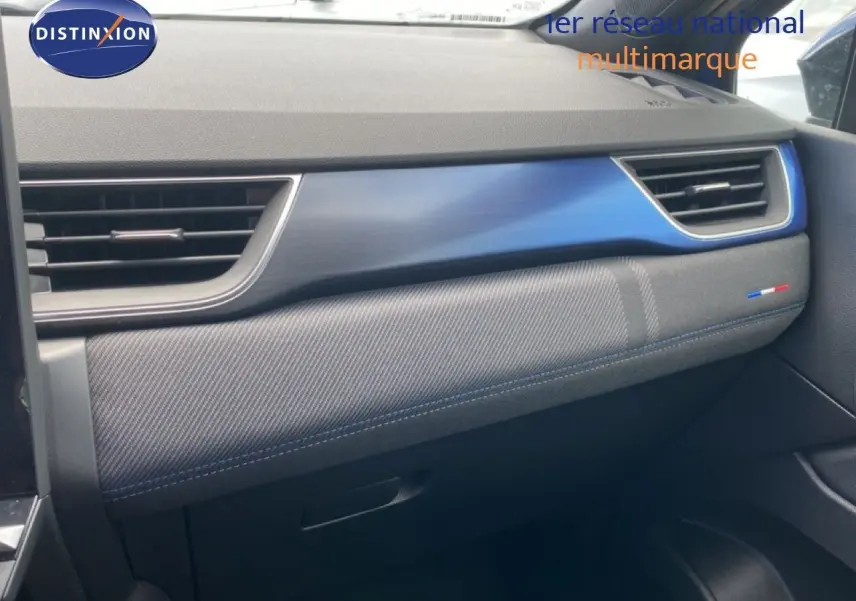 Détail de la planche de bord côté passager du Renault Symbioz 2025 avec insert bleu Iron Metal et surpiqûres bleues.