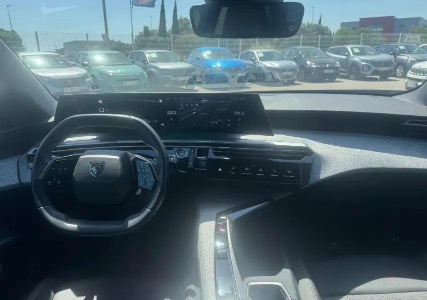 Vue intérieure avant du Peugeot 5008 Hybrid gris 2025, avec tableau de bord numérique et volant compact.