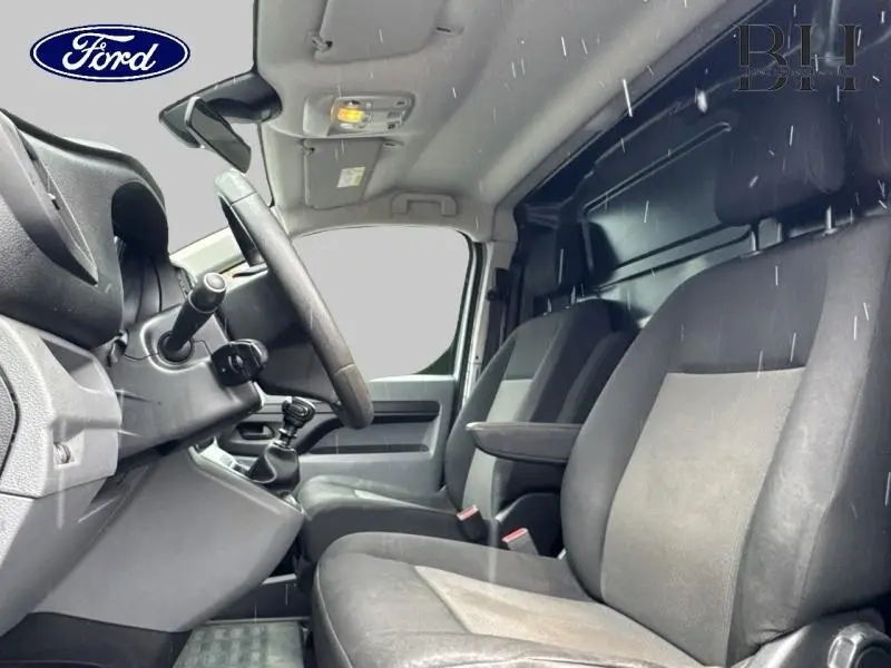 Vue intérieure côté conducteur du Citroën Jumpy gris aluminium, montrant les sièges avant et le volant.