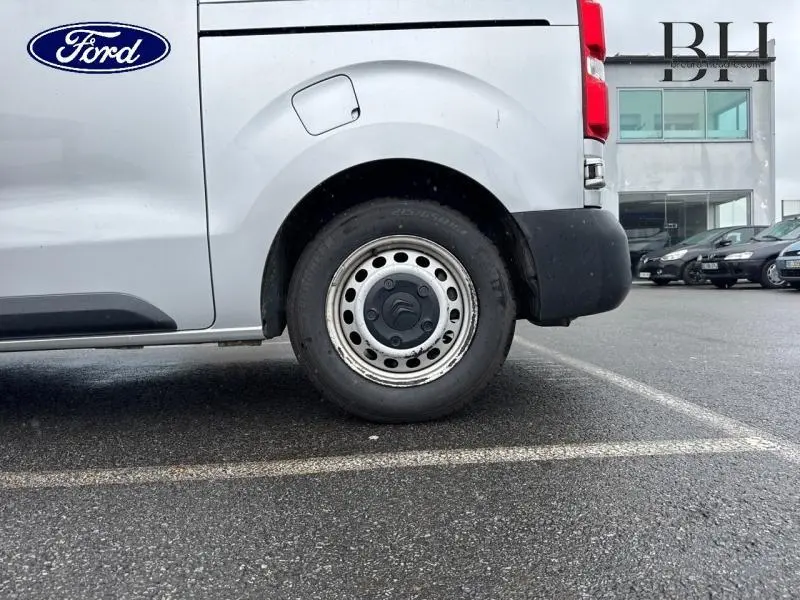 Vue latérale du côté gauche d'une Citroën Jumpy gris aluminium, mettant en valeur la roue arrière et la portière.