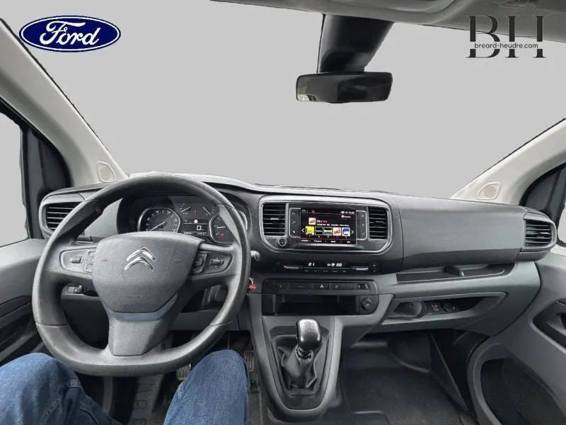 Vue intérieure avant du Citroën Jumpy gris aluminium de 2018, tableau de bord avec écran tactile et volant multifonctions.