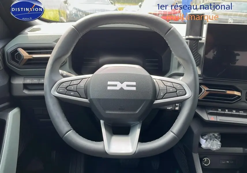 Vue centrée sur le volant multifonction noir du Dacia Duster 2025 avec tableau de bord et écran tactile visible.