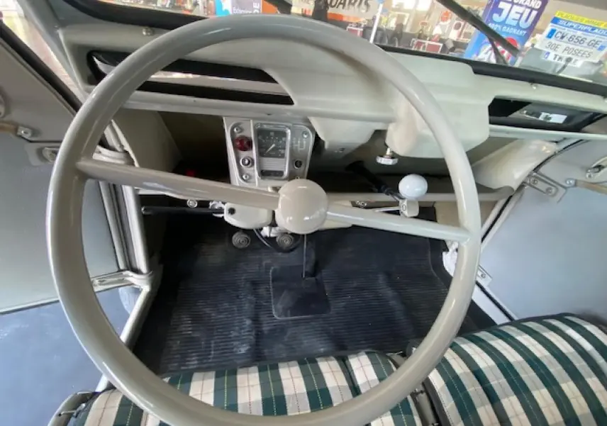 Vue intérieure centrée sur le volant beige clair et le tableau de bord minimaliste de la Citroën 2 CV 1968 rénovée.