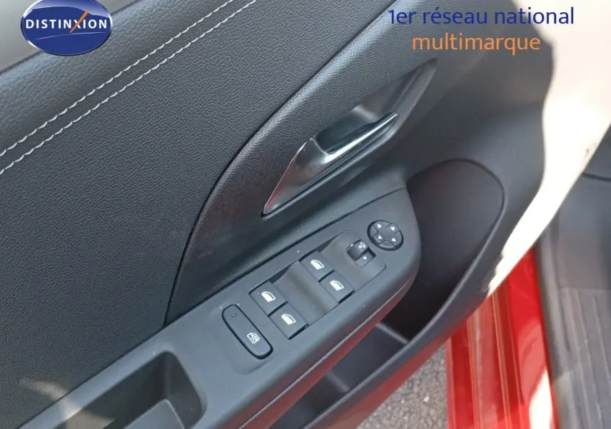 Gros plan sur la commande des vitres côté gauche d'une Opel Corsa rouge Kardio métal avec toit noir, porte ouverte.