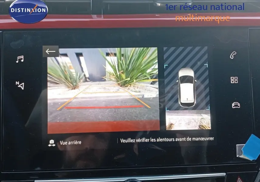 Écran multimédia affichant la caméra de recul et la vue 360° d'une Opel Corsa rouge à toit noir, intérieur moderne.