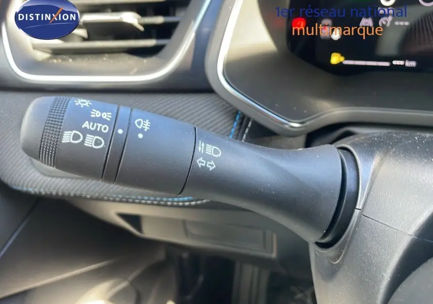 Gros plan sur la commande des phares et clignotants du Renault Captur E-Tech gris Rafale, intérieur noir avec tableau de bord numérique.