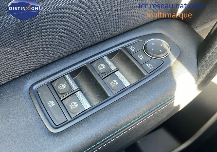 Gros plan sur les commandes des vitres électriques et rétroviseurs du côté gauche d'un Renault Captur gris Rafale métal toit noir.