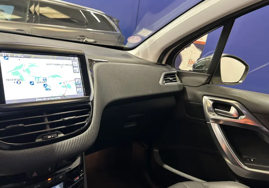 Vue intérieure côté passager du tableau de bord et écran GPS d'une Peugeot 2008 blanche de 2014 avec détails de la porte et ventilation.