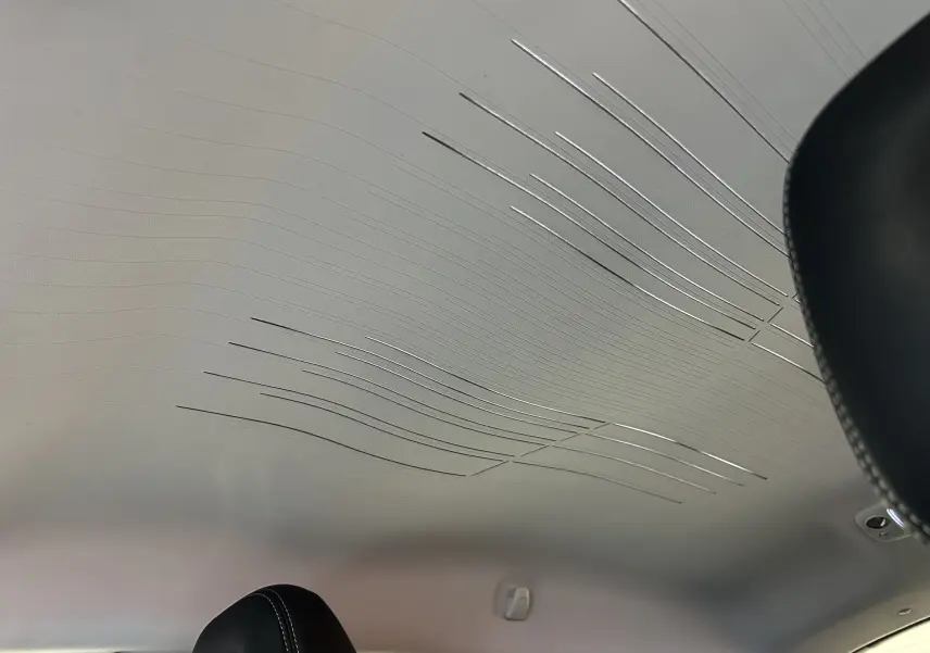 Plafond intérieur clair avec motifs ondulés métalliques, vue partielle des appuis-tête noirs du Peugeot 2008 blanc 2014.