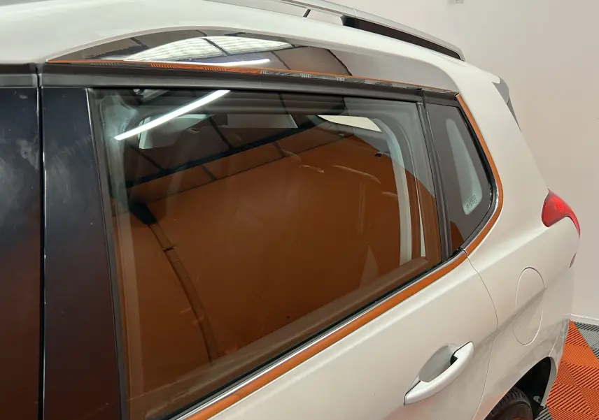 Vue latérale droite arrière d'un Peugeot 2008 blanc de 2014 avec vitres teintées et poignée de porte visible.