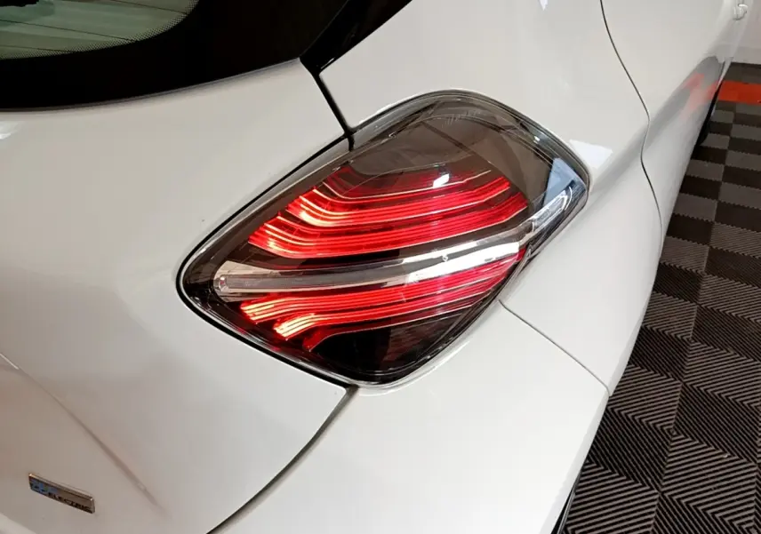 Gros plan sur le feu arrière droit rouge d’une Renault ZOE blanche, version électrique de 2021, sur sol à damier.