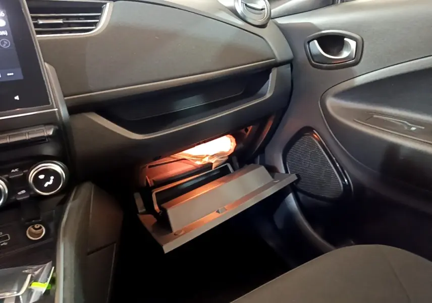 Intérieur de la Renault ZOE Business 2021, vue côté passager avec boîte à gants ouverte et éclairage intérieur visible.