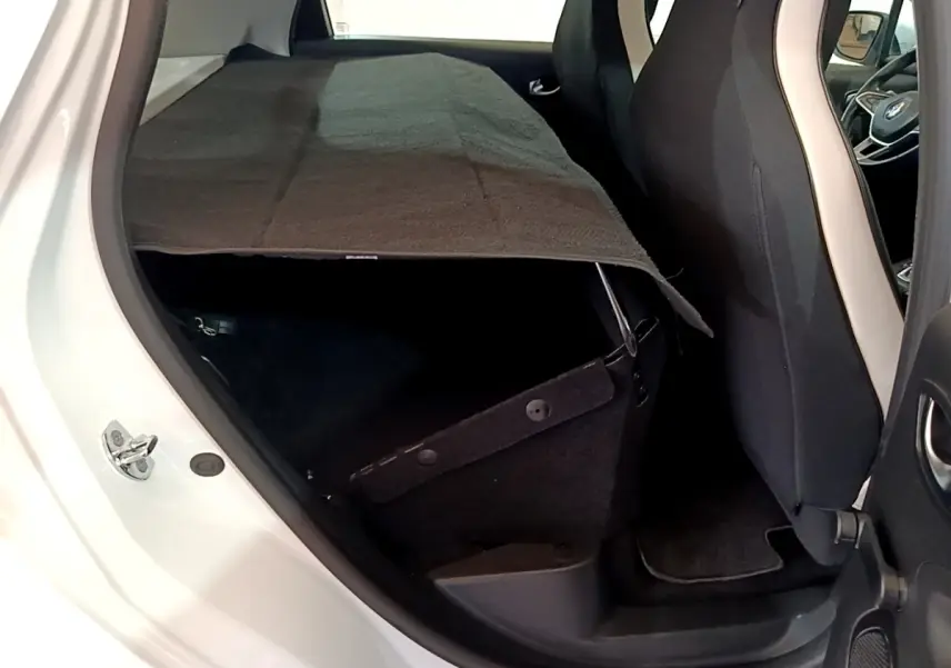 Vue intérieure côté gauche arrière de la Renault ZOE Business R110 blanche, montrant les sièges et le coffre partiellement couvert.