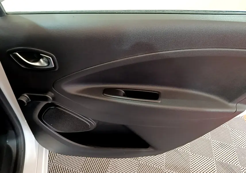 Vue intérieure sur la porte côté gauche noire de la Renault ZOE Business R110 blanche, avec poignée et haut-parleur intégrés.