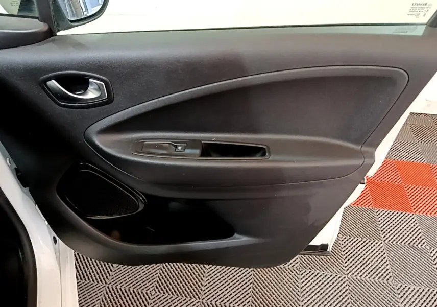 Vue intérieure côté gauche de la porte avant blanche de la Renault ZOE Business R110 avec commande de fenêtre et haut-parleur intégré.