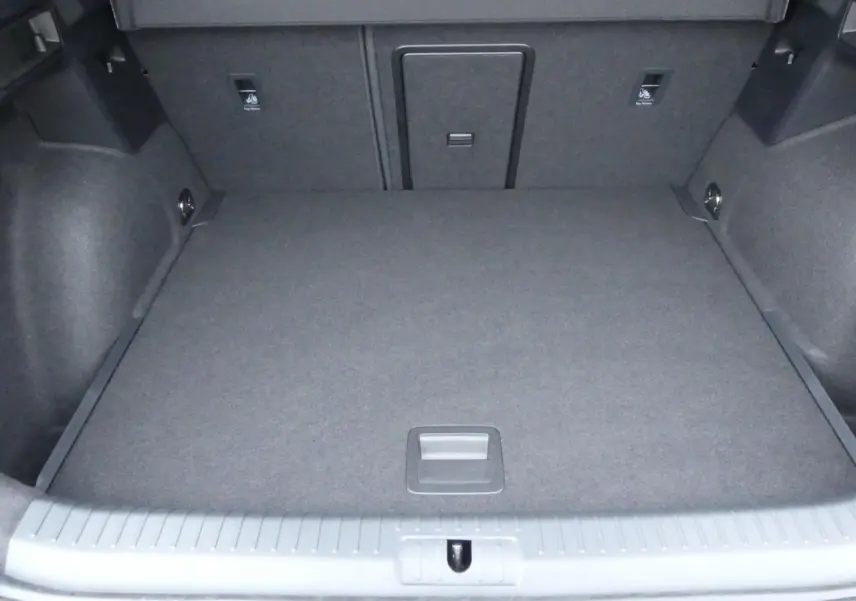 Coffre spacieux vu de face, revêtement gris foncé, avec trappe centrale et ancrages visibles.