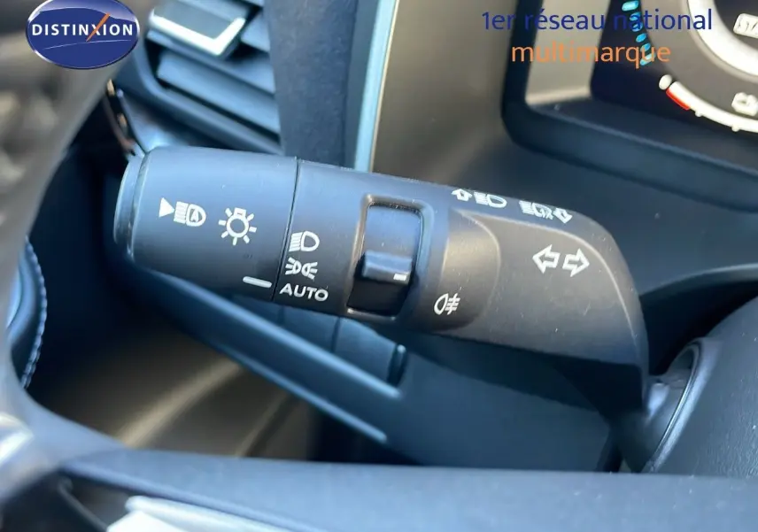 Gros plan sur la commande des feux et clignotants à gauche du volant dans un Nissan Qashqai blanc nacré 2025.