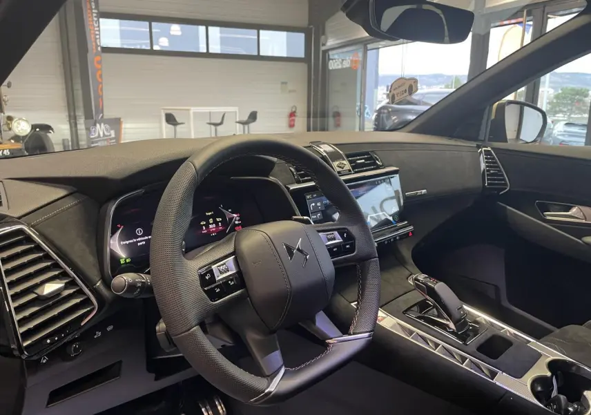 Vue intérieure côté conducteur du DS7 Crossback gris titanium, mettant en valeur le volant cuir perforé et l'écran tactile central.
