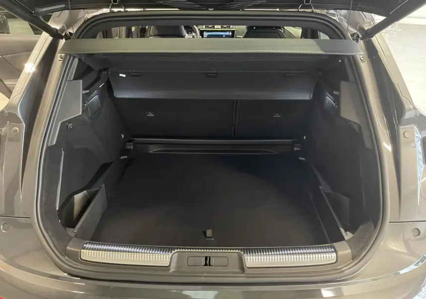 Coffre ouvert vu de l'arrière d'un DS7 Crossback gris titanium avec seuil de coffre chromé et intérieur noir.