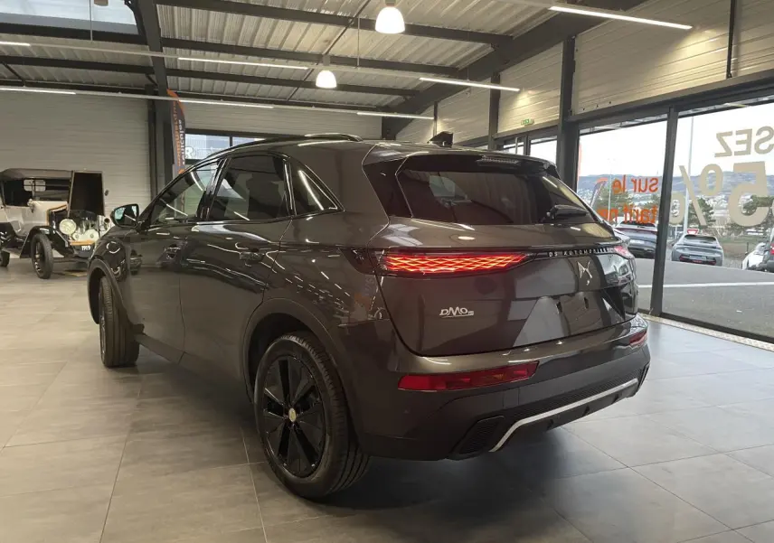 Vue 3/4 arrière droit du DS7 Crossback gris titanium avec feux arrière LED et jantes noires en showroom.