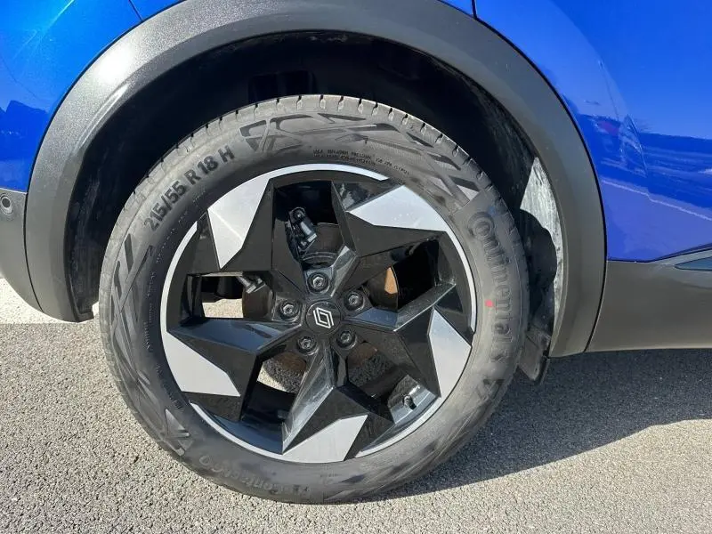 Gros plan sur la roue arrière droite du Renault Captur 2025 Bleu Iron/Noir Étoilé avec jante noire et argentée au design étoilé.