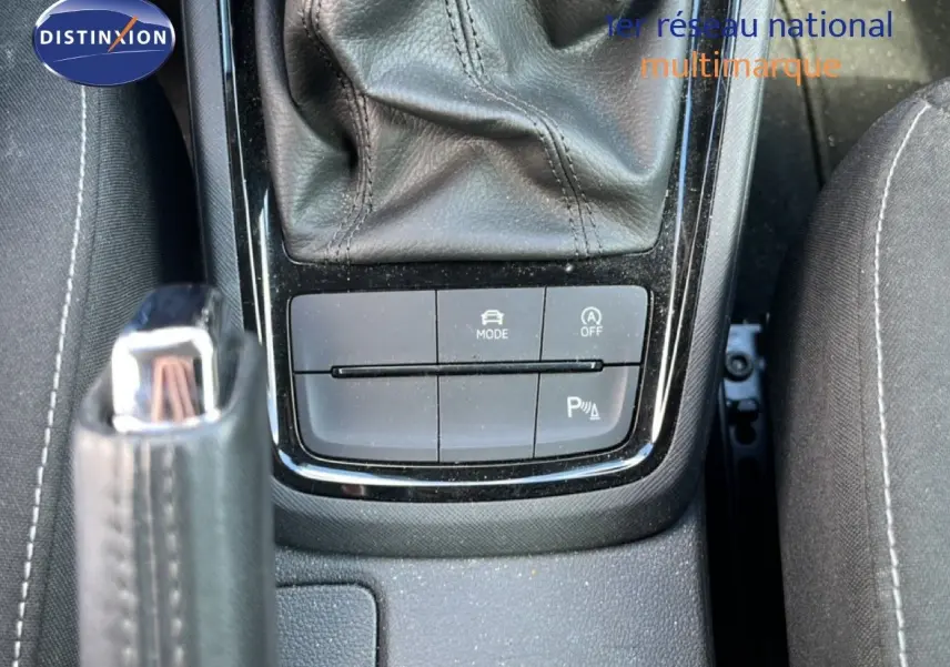 Gros plan sur la console centrale de la Skoda Scala gris magnétique, montrant levier de frein à main et boutons de mode et parking.