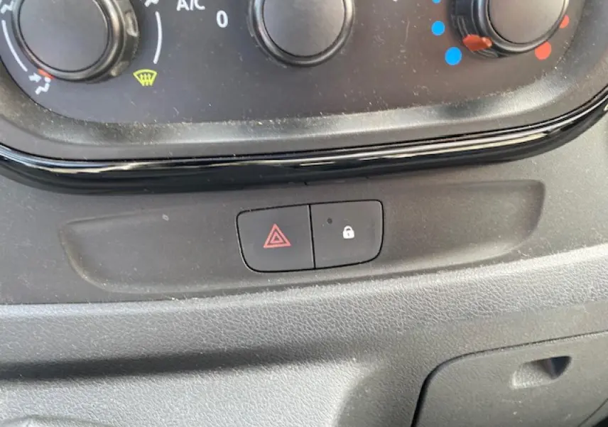 Gros plan sur les commandes de climatisation et les boutons de verrouillage et warning de l'Opel Vivaro blanc de 2018.