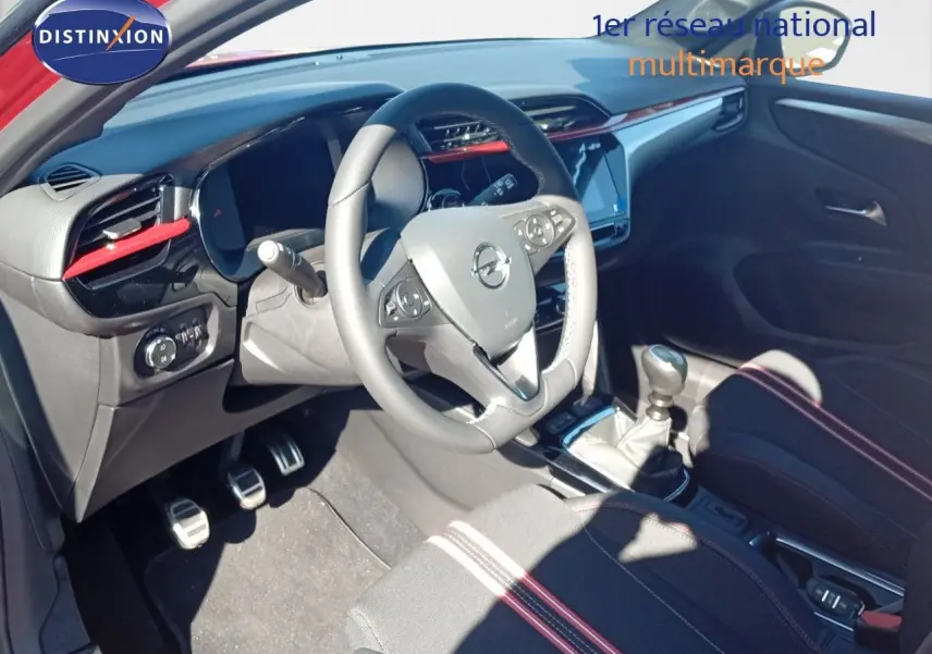 Intérieur de l'Opel Corsa 2023 vu côté conducteur, volant multifonction et détails rouges sur tableau de bord.