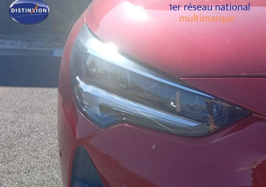 Gros plan sur le phare avant gauche d'une Opel Corsa rouge Kardio métal avec toit noir, modèle 2023.